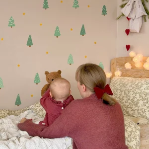 Lapsi istuu sängyllä ja osoittaa seinäkoristeita, joissa on joulu- ja luontoaiheita.