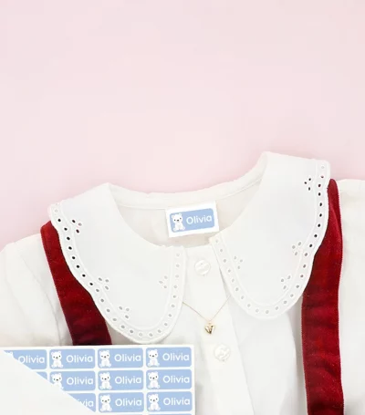 Lasten kengät ja mekko, joissa on nimitarroja, ympärillä lumihiutalekoristeita.