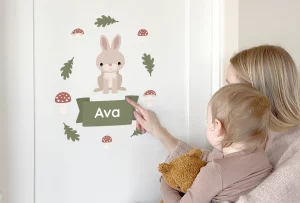 Söpöt lasten ovitarrat, joissa on kani ja nimi ”Ava” vihreällä kyltillä, vihreiden lehtien ja sienten ympäröimänä. Täydellinen lastenhuoneen personointiin ja kodikkaan tunnelman luomiseen.