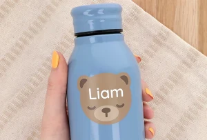 Personoitu sininen juomapullo, jossa on söpö karhun kuva ja nimi Liam. Pullo on käsissä ja taustalla näkyy vaaleaa kangasta, mikä giruuttaa esille lasten tuotteiden ystävällisen ja leikkisän tunnelman. Tämä tuote on täydellinen lahjaidea lapsille ja sopii erinomaisesti myös koulun käyttöön.