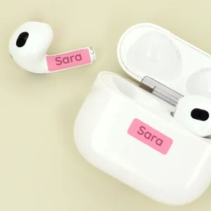 Navetikkuja nimellä Sara AirPods-toteutuksella, jossa on vaaleanpunaiset tarrat, jotka lisäävät henkilökohtaisuutta. Tämä tuote on loistava lisä yksilöllisiin lahjaksi, lastenhuoneen sisustukseen tai käytettäväksi.